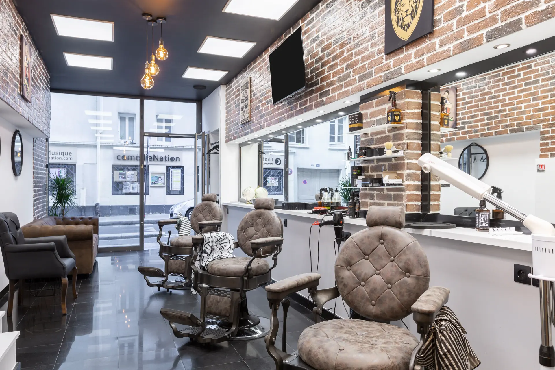 Intérieur du salon Gents Coiffure — fauteuils barbier et mur de briques