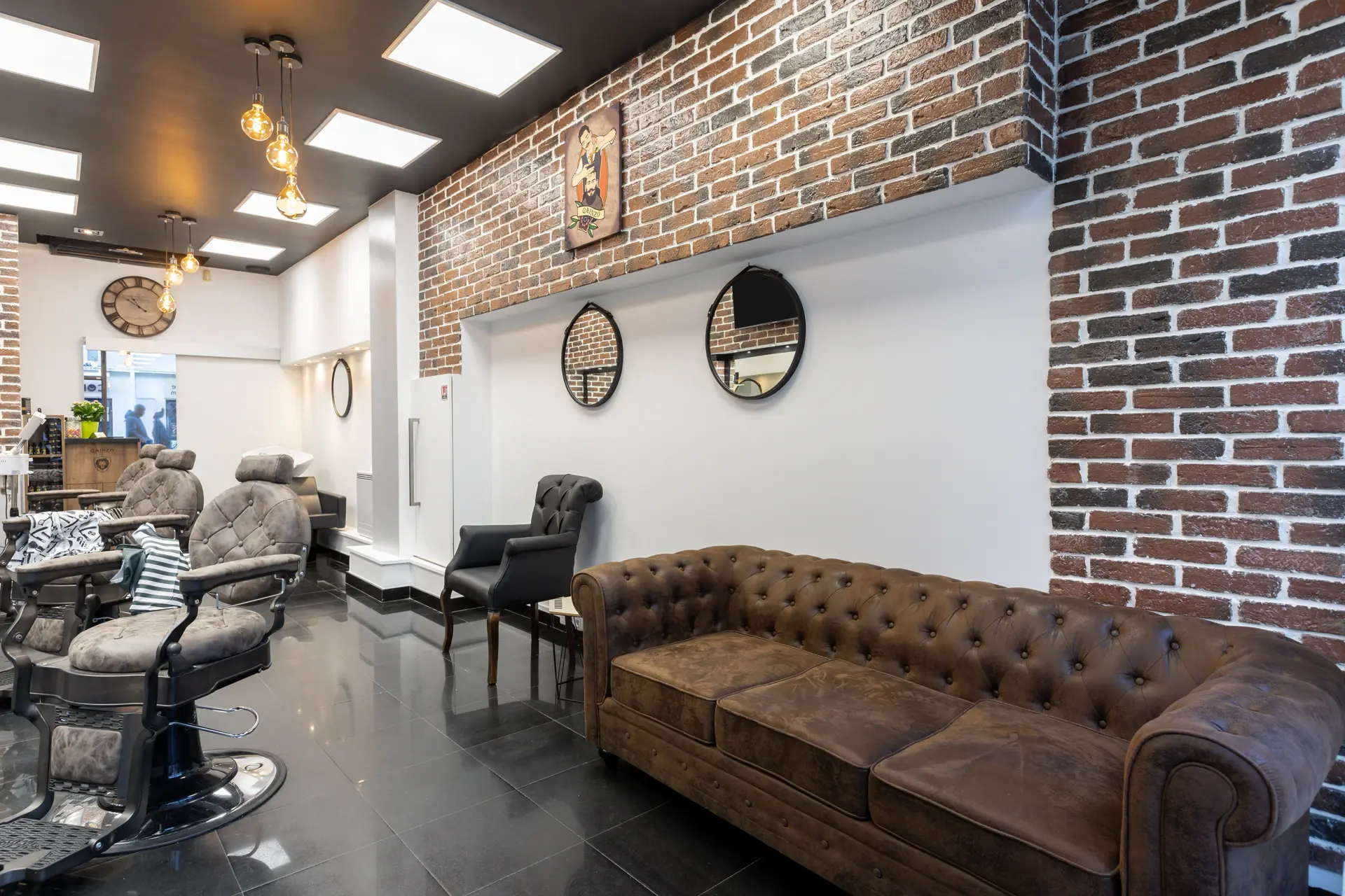 Espace lounge Gents Coiffure — canapé Chesterfield et déco industrielle